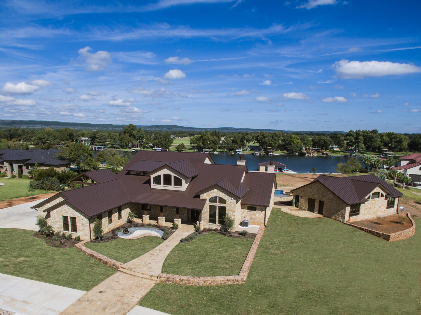 Aerial view of a custom home with a sophisticated stone exterior nestled on the lake, Lake LBJ TX